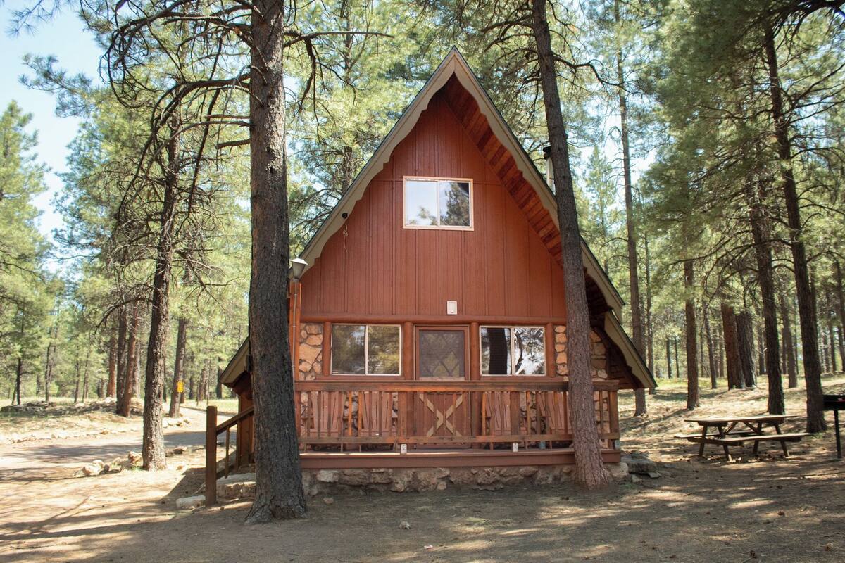 A cabin with a triangular roof, large windows, and a wooden deck.