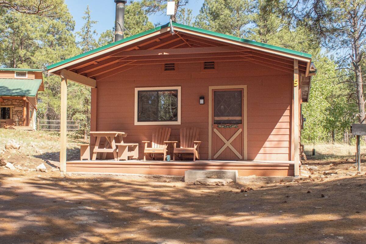 A small wooden cabin with a porch, two windows, and a door.