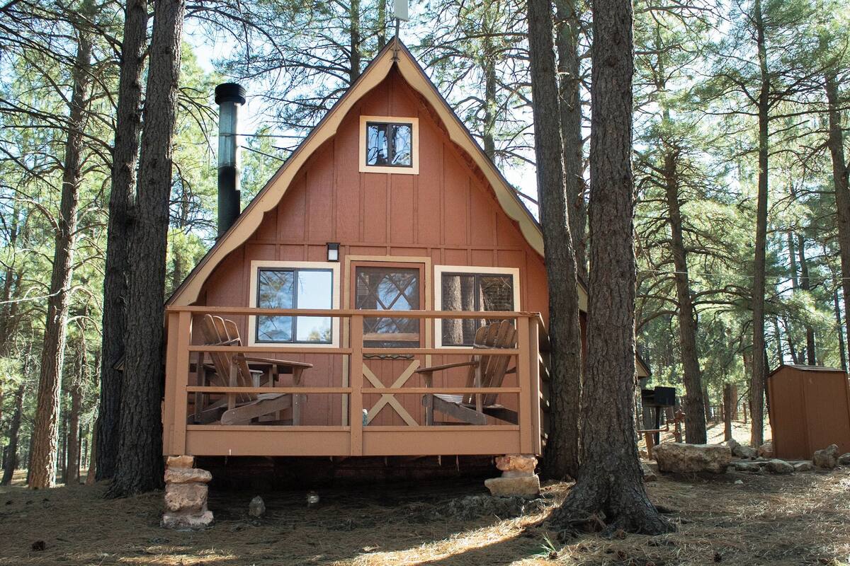 A wooden cabin with a balcony, surrounded by trees.