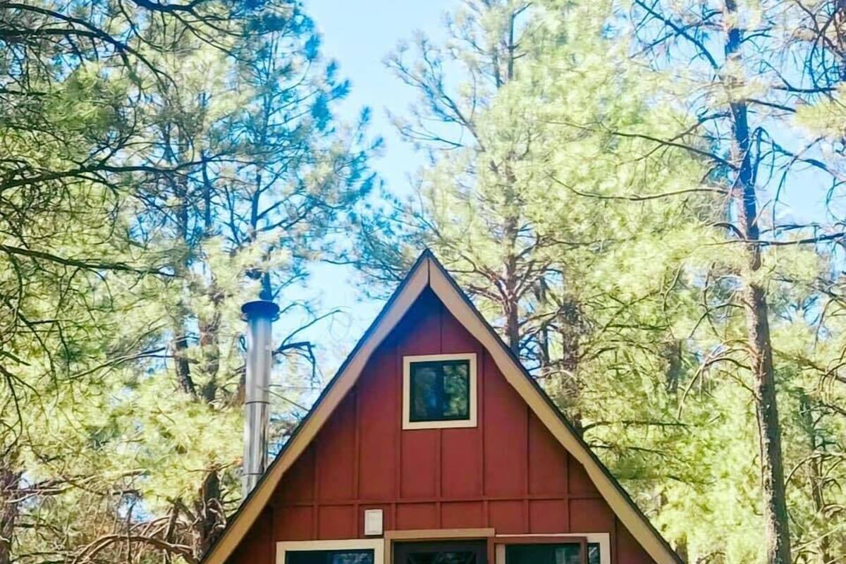 A cabin with a wooden deck, surrounded by trees.