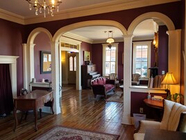 Uma sala de estar espaçosa com um piano de cauda, um sofá vermelho e um candelabro.