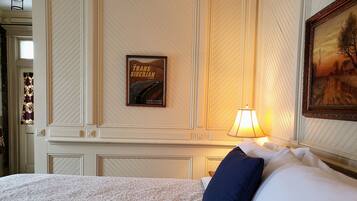 A hotel room with a bed, a framed picture of the Trans Siberian Railway, and a lamp.