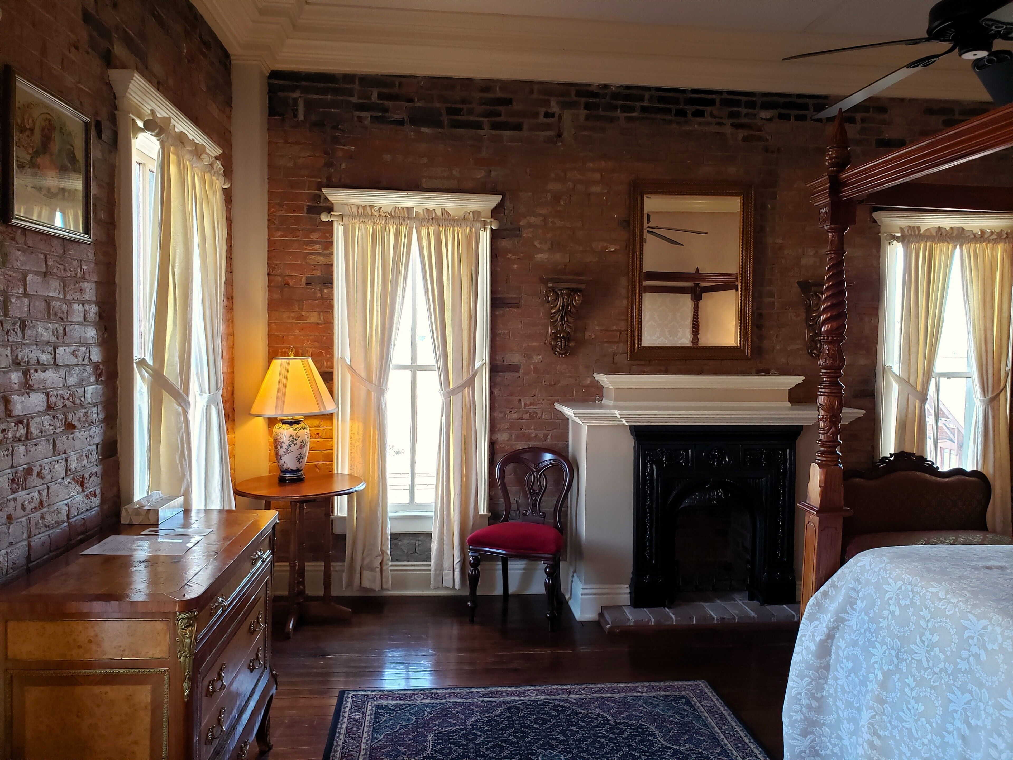 Une pièce avec un mur en briques, une cheminée, un lit et une commode en bois.