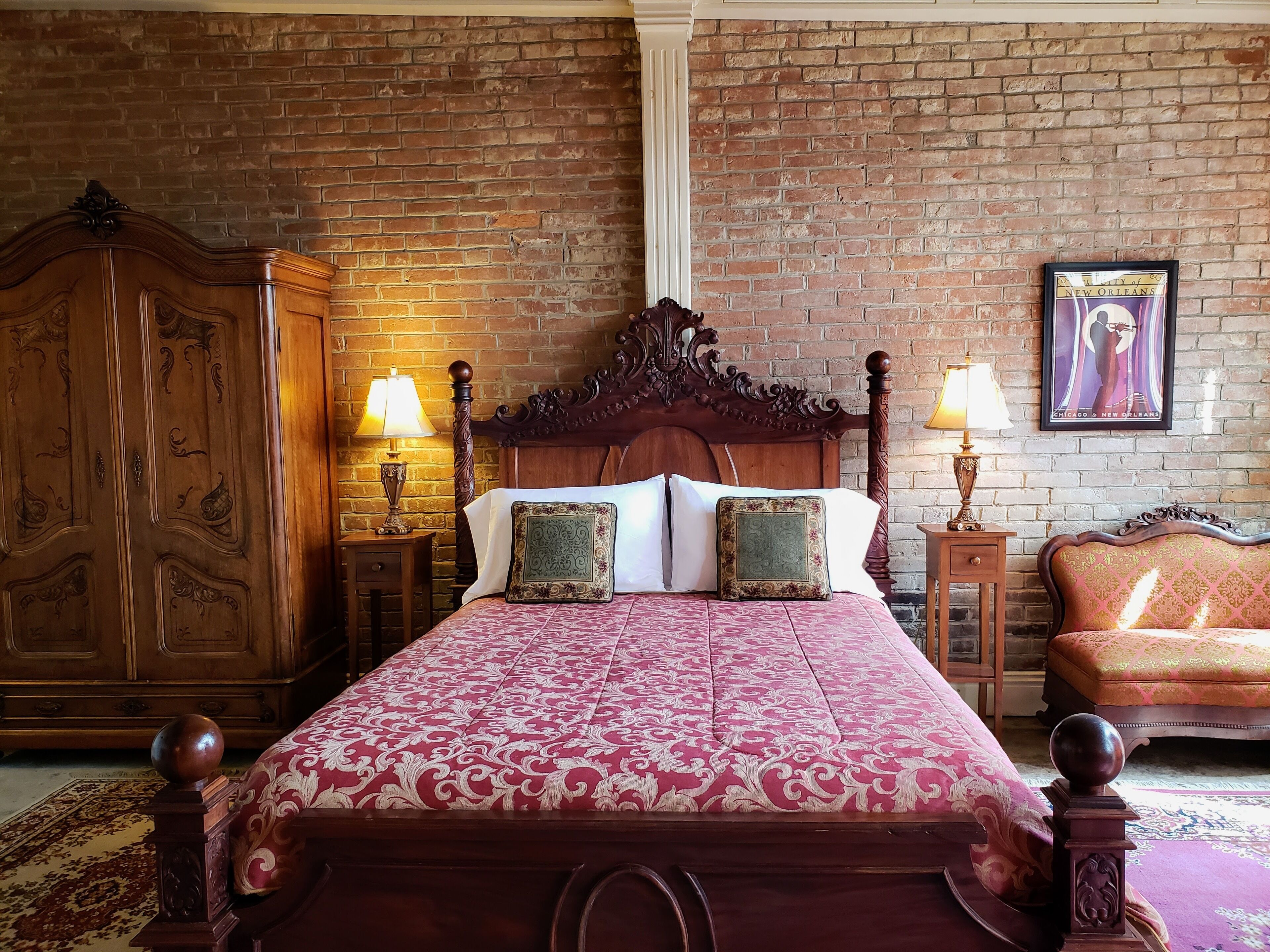 A bedroom with a large wooden bed, two nightstands with lamps, a wooden wardrobe, and a framed picture on the wall.