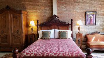 A bedroom with a large wooden bed, two nightstands with lamps, a wooden wardrobe, and a framed picture on the wall.