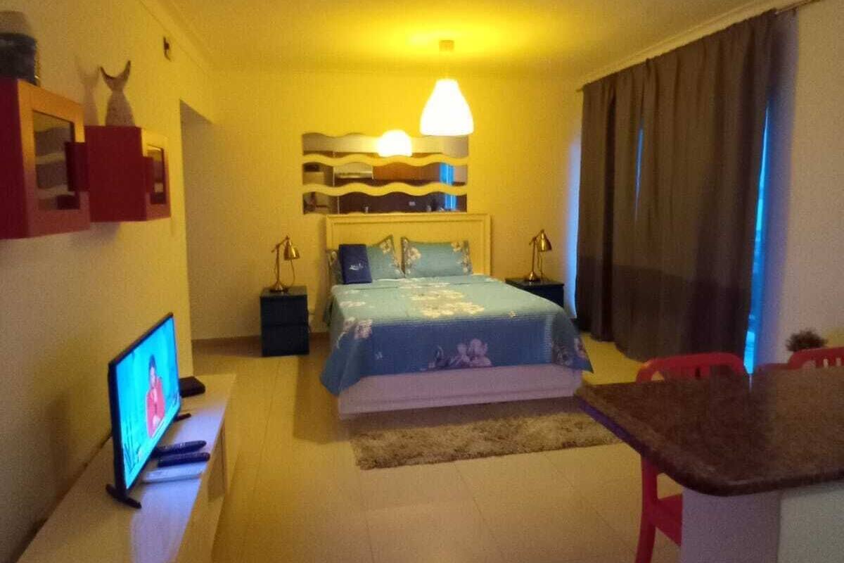 Una habitación de hotel con una cama, televisión, escritorio y una silla.