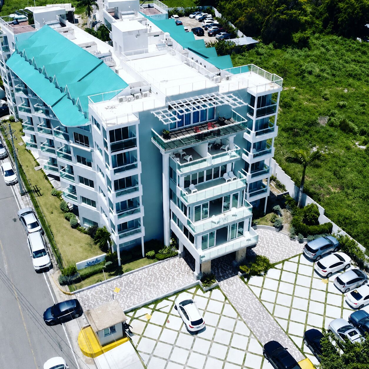 A multi-story hotel with a parking area and a green lawn.
