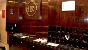 A reception desk with a wooden finish, a large 'HR' sign, a glass display case with items, and a small framed certificate on the wall. - Hotel República (San Miguel de Tucuman)