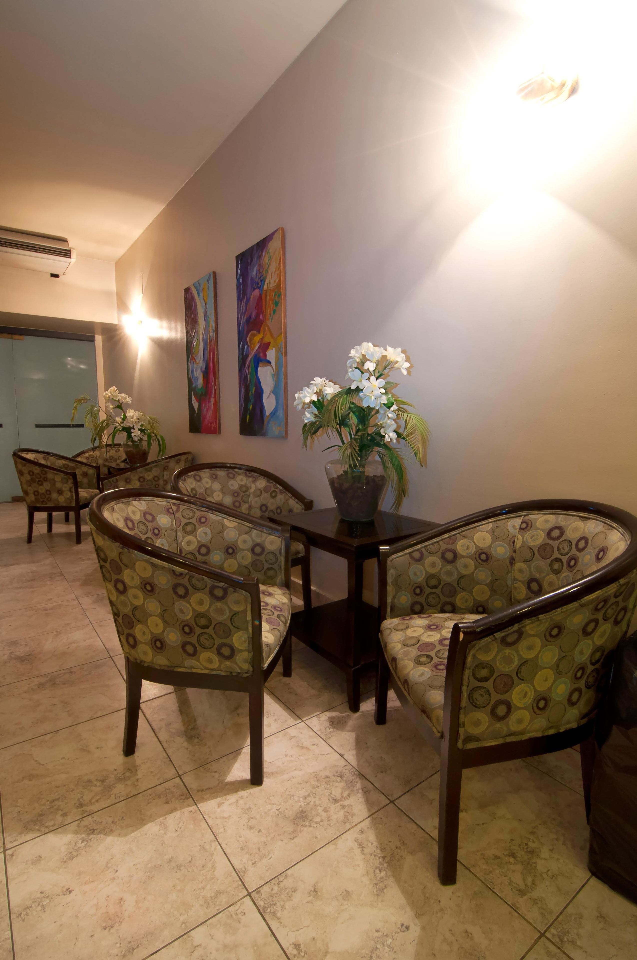 Un comedor con una mesa y cuatro sillas, una planta en maceta y dos cuadros colgados en la pared.