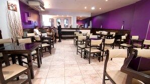A restaurant with multiple tables and chairs, a counter, and a tiled floor. - Hotel República (San Miguel de Tucuman)