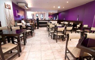 Un restaurante con varias mesas y sillas, una barra y piso de baldosas.