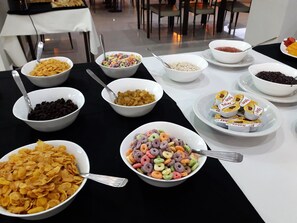 Een buffet met diverse soorten eten, zoals ontbijtgranen, fruit en snacks.