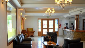 A lobby with a reception desk, seating area, and a chandelier. - Cumbres Hotel (El Bolson)