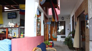 A cozy interior with a reception desk, wooden furniture, and potted plants. - Galapagos Best Hostel (Puerto Ayora)