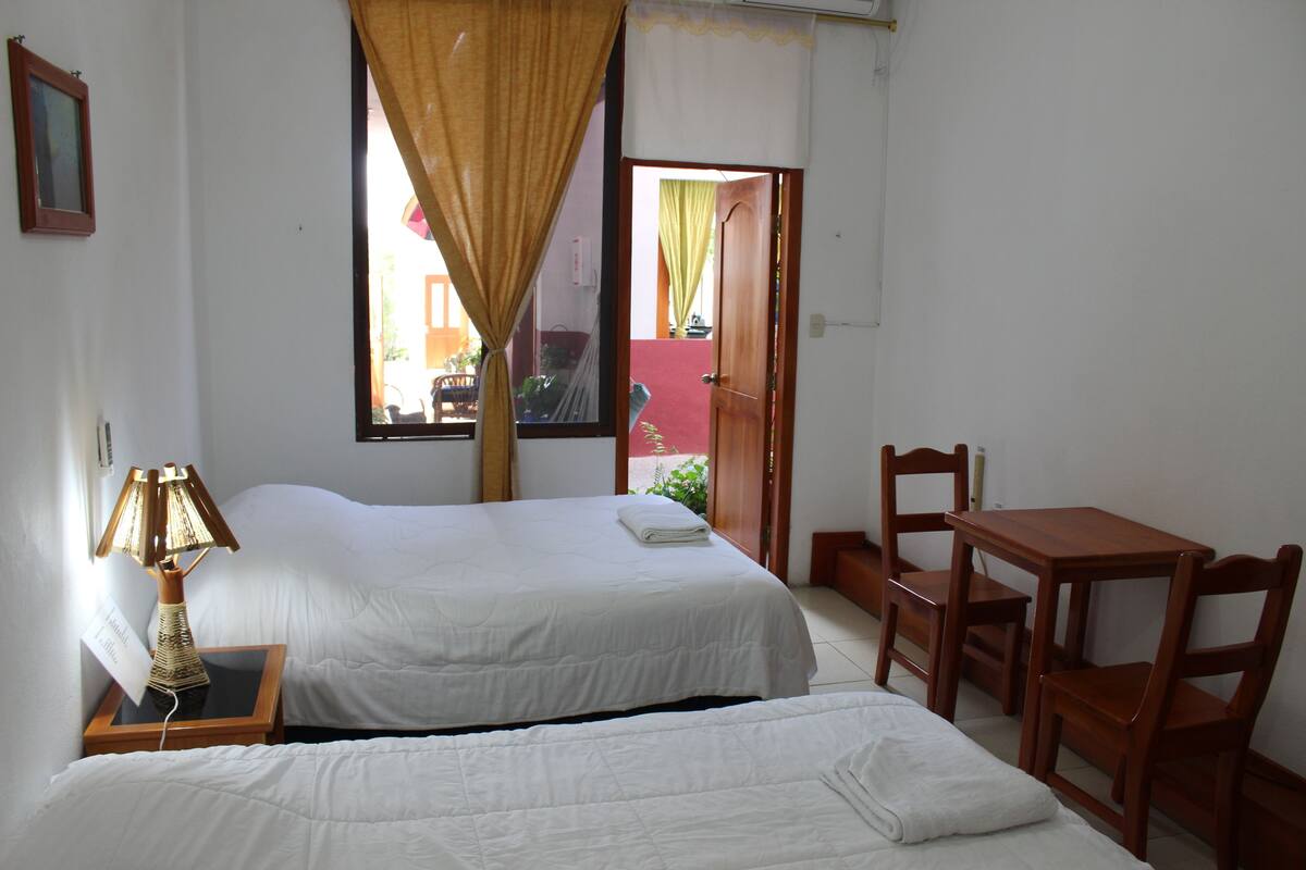A hotel room with two beds, a desk, and a chair.