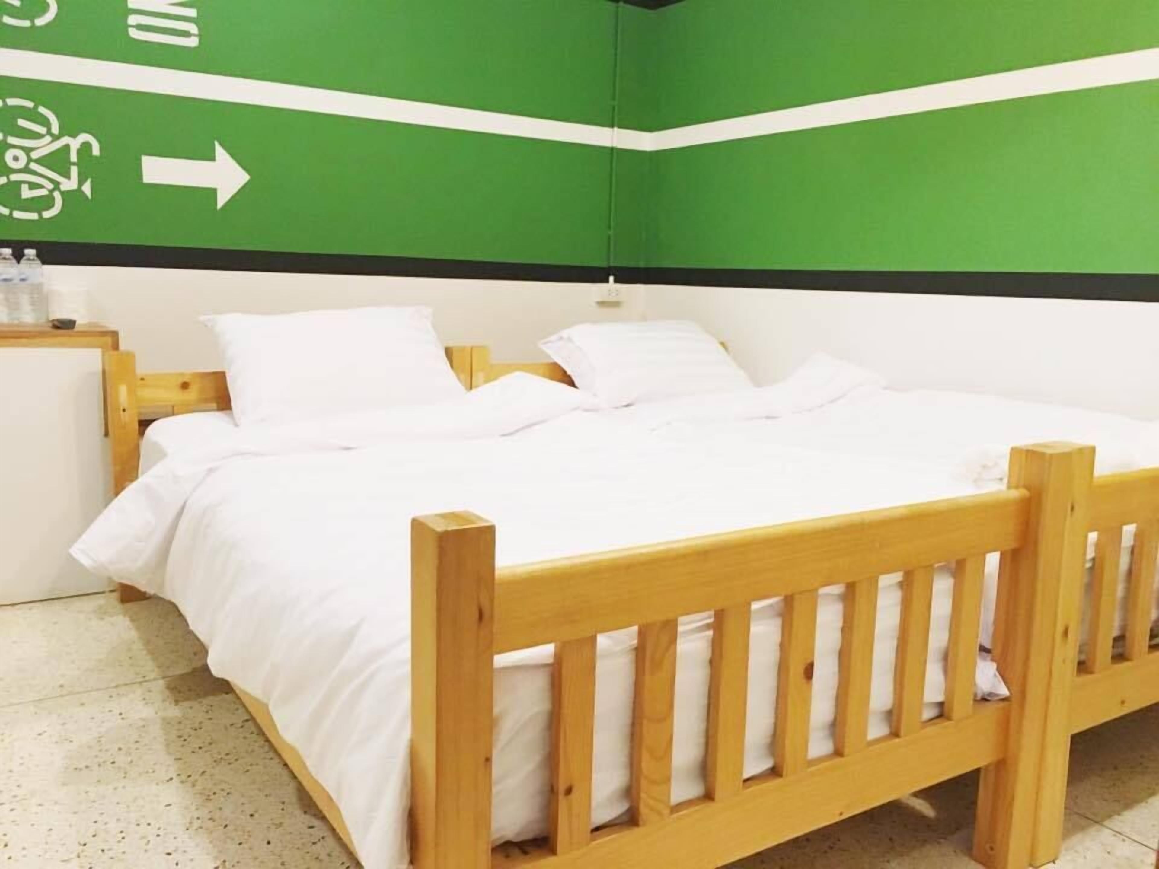 A single bed with white bedding in a room with green walls and a white ceiling.