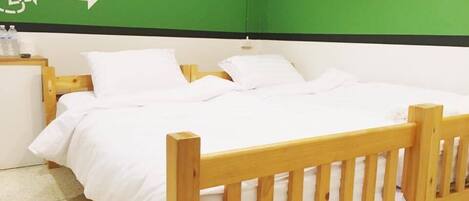 A single bed with white bedding in a room with green walls and a white ceiling.