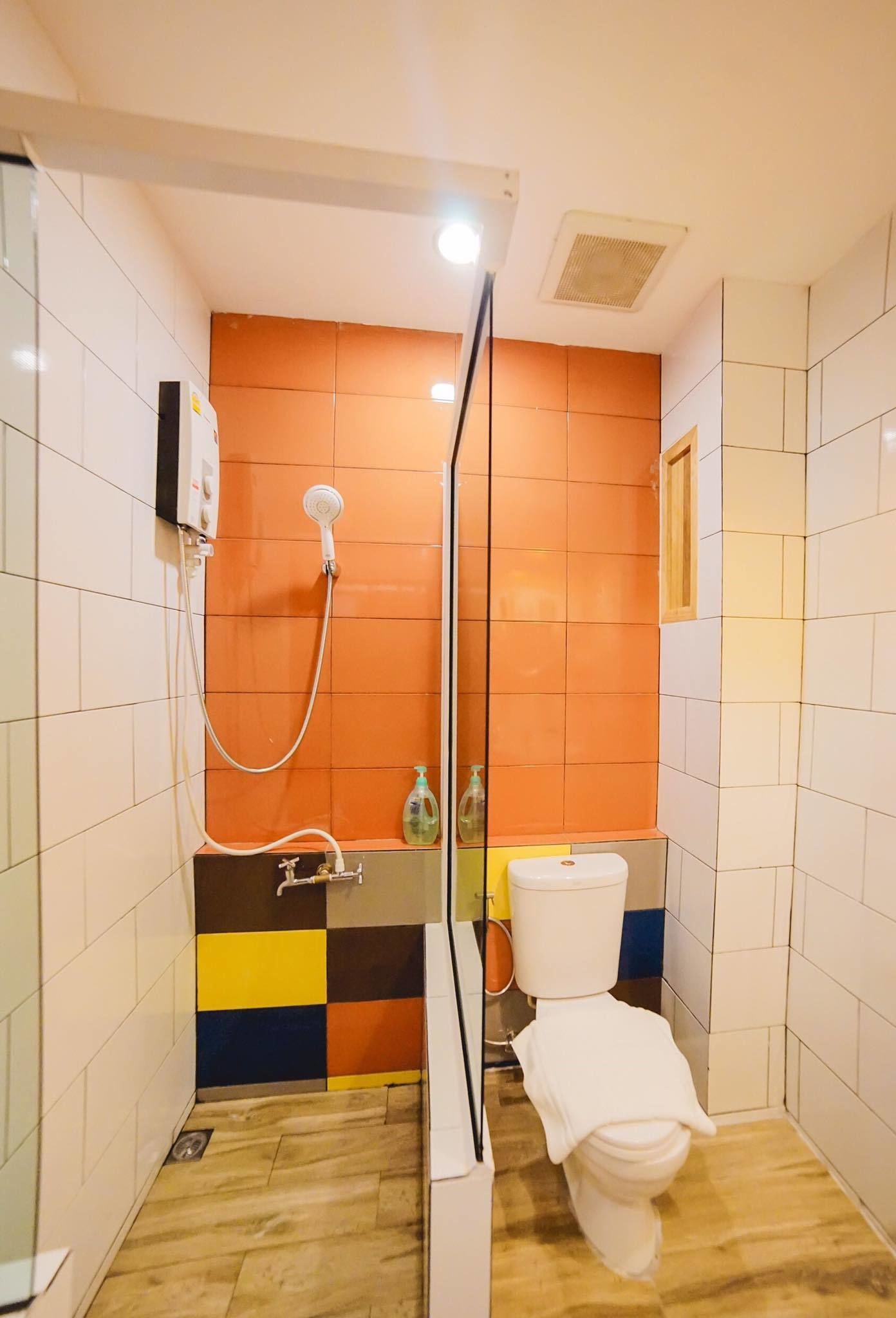 A small, brightly colored bathroom with a shower, toilet, and a sink.