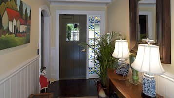 A hallway with a wooden bench, a door with stained glass, and a table with lamps.