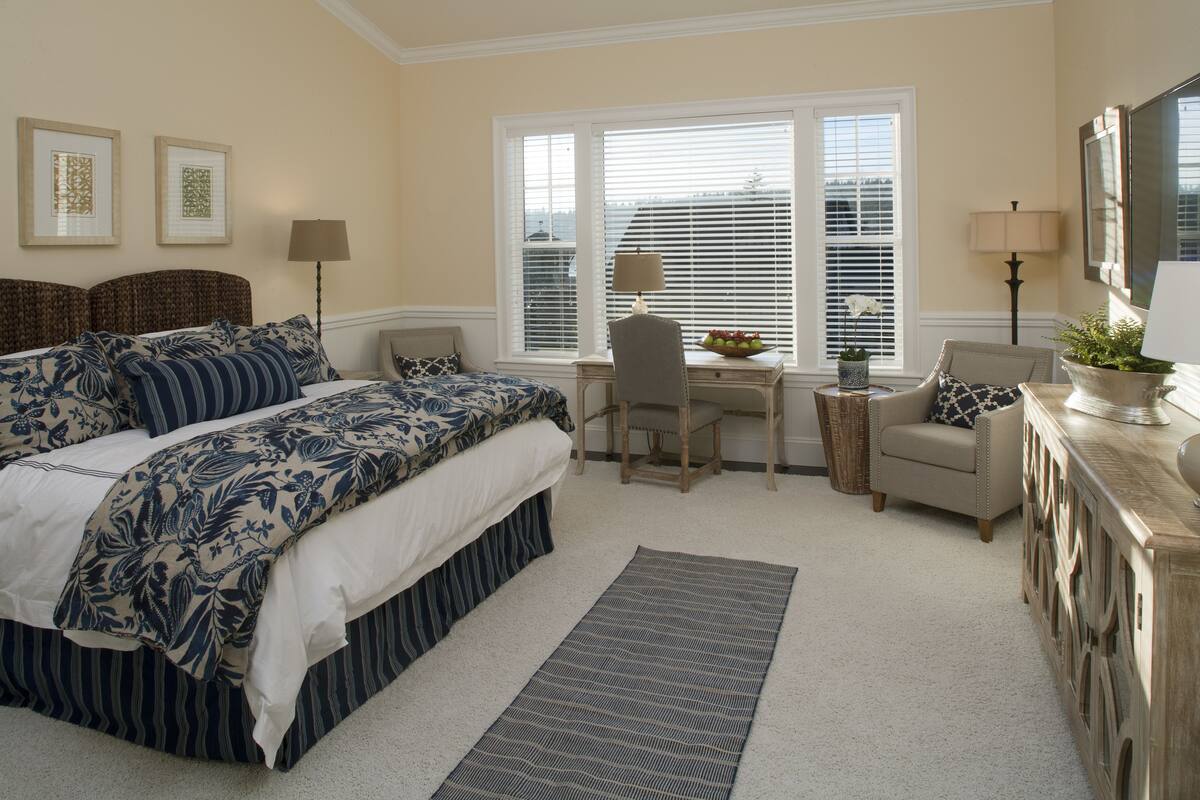 A bedroom with a large bed, a desk, a chair, a sofa, and a television.