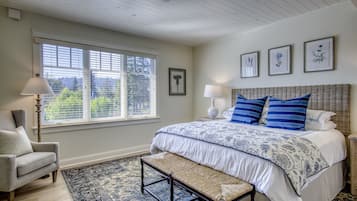 Une chambre à coucher avec un grand lit, un banc, une chaise et une fenêtre avec des stores.