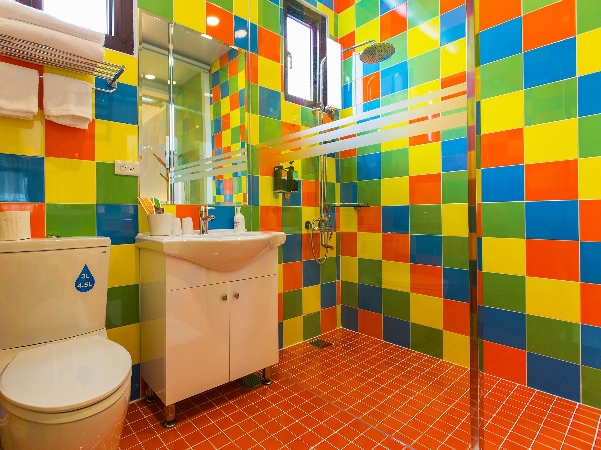 Un baño con baldosas coloridas, un lavamanos, un inodoro y una ducha.