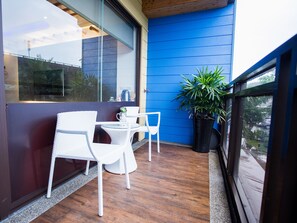 A balcony with a wooden floor, white wicker chairs, a small table, and a potted plant. - Star of Bethlehem BnB (Wujie)
