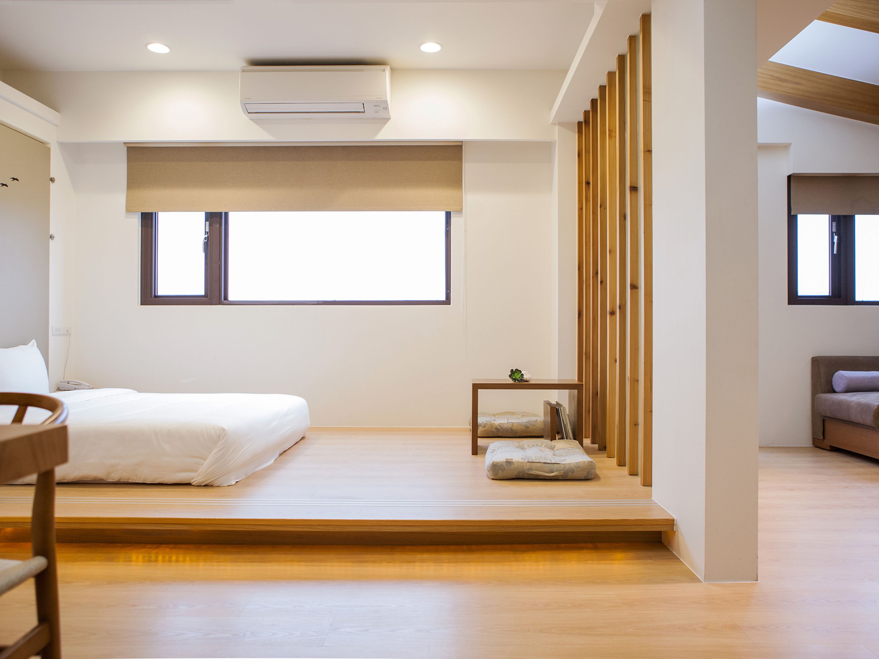 Una habitación de hotel moderna con cama, mesita de noche y una pequeña zona de estar.