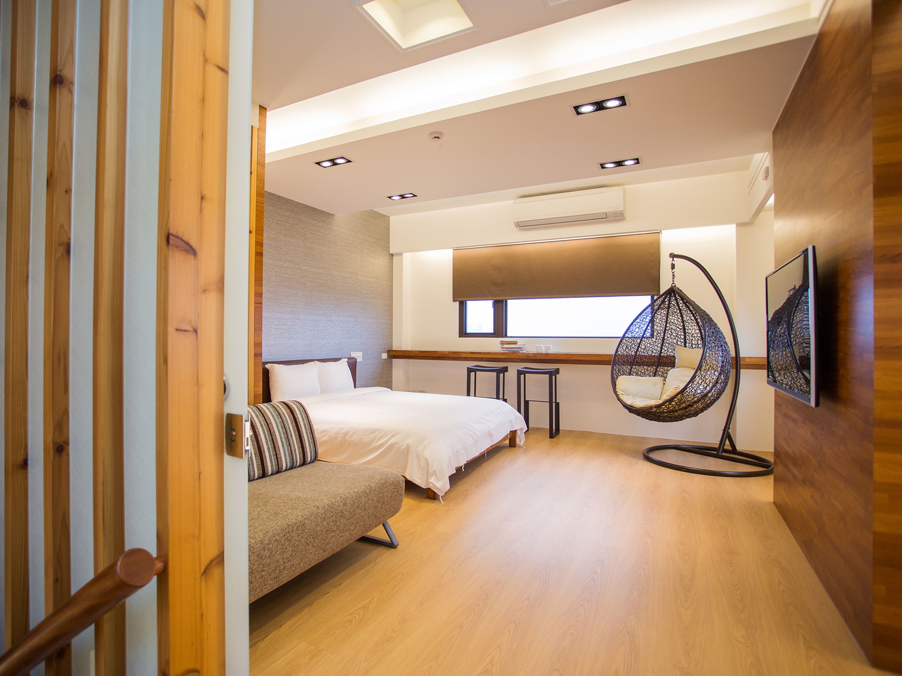 Un dormitorio moderno con una cama, un sillón colgante y un pequeño rincón de estar.