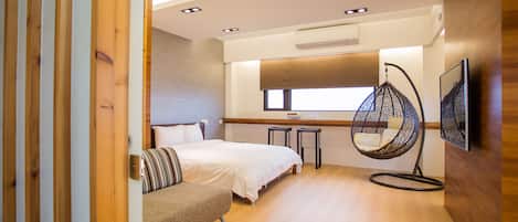 Un dormitorio moderno con una cama, un sillón colgante y un pequeño rincón de estar.