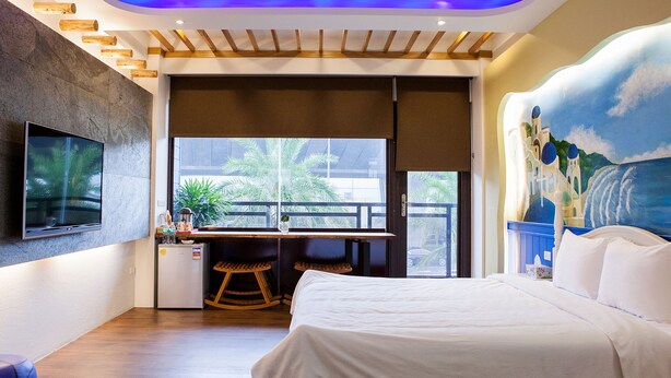 A modern hotel room with a bed, a desk, a TV, and a balcony with a view of palm trees. - Star of Bethlehem BnB (Wujie)
