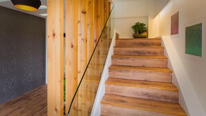 A wooden staircase with glass railings, a hanging pendant light, and artwork on the walls. - Star of Bethlehem BnB (Wujie)