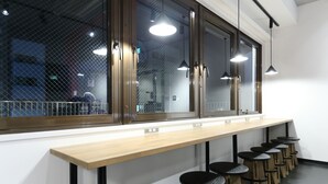 A long wooden bar with black stools and pendant lights. - Oak Hotel Edo (Tokyo)