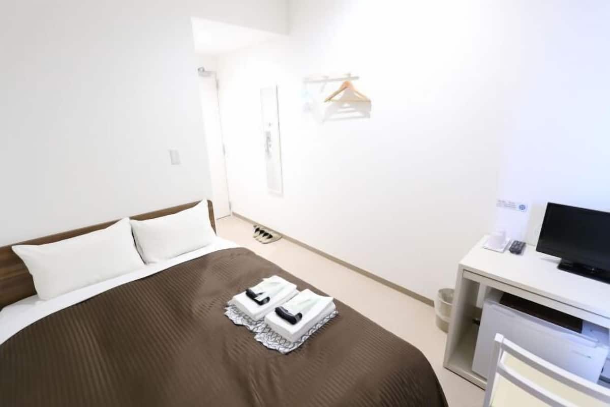 A hotel room with a bed, a desk with a computer, and a TV.