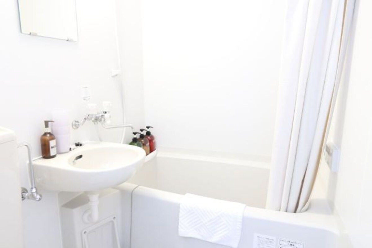 A bathroom with a white sink, a bathtub, and a towel hanging on the wall.