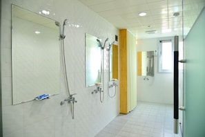 Un baño moderno con múltiples cabezales de ducha, un espejo y un inodoro.