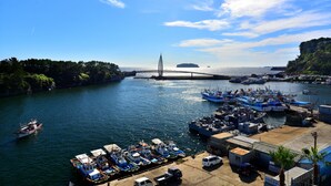 A harbor with boats docked, a bridge in the background, and a clear sky. - Seom Guesthouse - Hostel (Seogwipo)