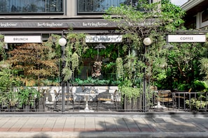 A restaurant with outdoor seating, labeled 'BRUNCH' and 'COFFEE', surrounded by lush greenery and plants. - Volve Hotel Bangkok (Bangkok)