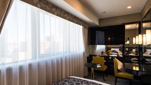 A hotel room with a bed, a desk, a chair, a large mirror, and a window with sheer curtains. - APA Hotel Iidabashi Ekimae (Tokyo)