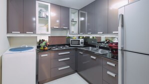 Eine moderne Küche mit grauen Schränken, einer Mikrowelle, einem Spülbecken und einem Kühlschrank.