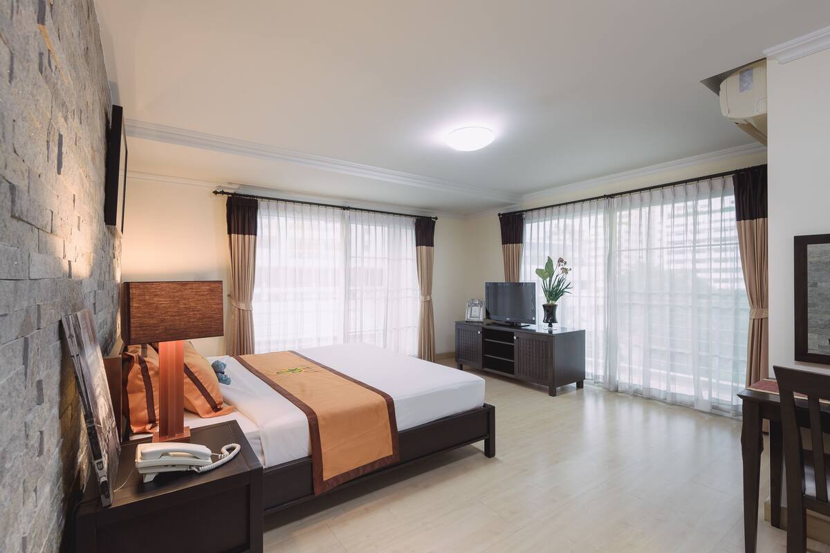 Une chambre d’hôtel avec un grand lit, un bureau, une télévision et une plante en pot.