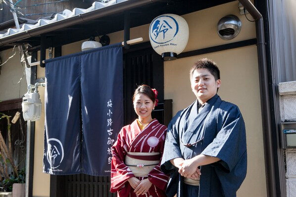 A traditional Japanese building with a black and white sign, a decorative lantern, and a blue curtain.