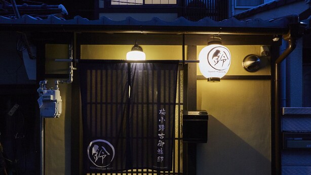 Un bâtiment traditionnel japonais, doté d’une porte noire, d’une enseigne lumineuse et d’un petit marchepied menant à l’entrée.