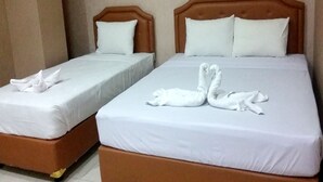 Two beds with white linens and wooden headboards, each with a pillow and a towel arranged in a swan shape. - DeKopen Rooms & Convention (Malang)
