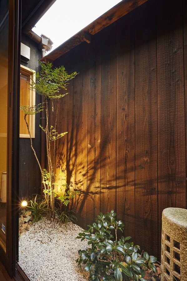 Stunning exterior wall with a vertical slat design and a window, set amidst a tranquil garden area.