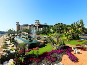A hotel with a large building, a fountain, and well-maintained gardens with various plants and flowers. - Country Garden Golden Beach Spring Hotel (Lingao)