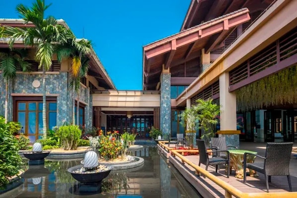 A hotel courtyard with a central water feature, outdoor seating, and tropical plants. - Country Garden Golden Beach Spring Hotel (Lingao)