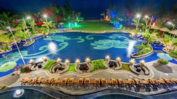 A large, circular pool with a lotus design, surrounded by lounge chairs and palm trees.