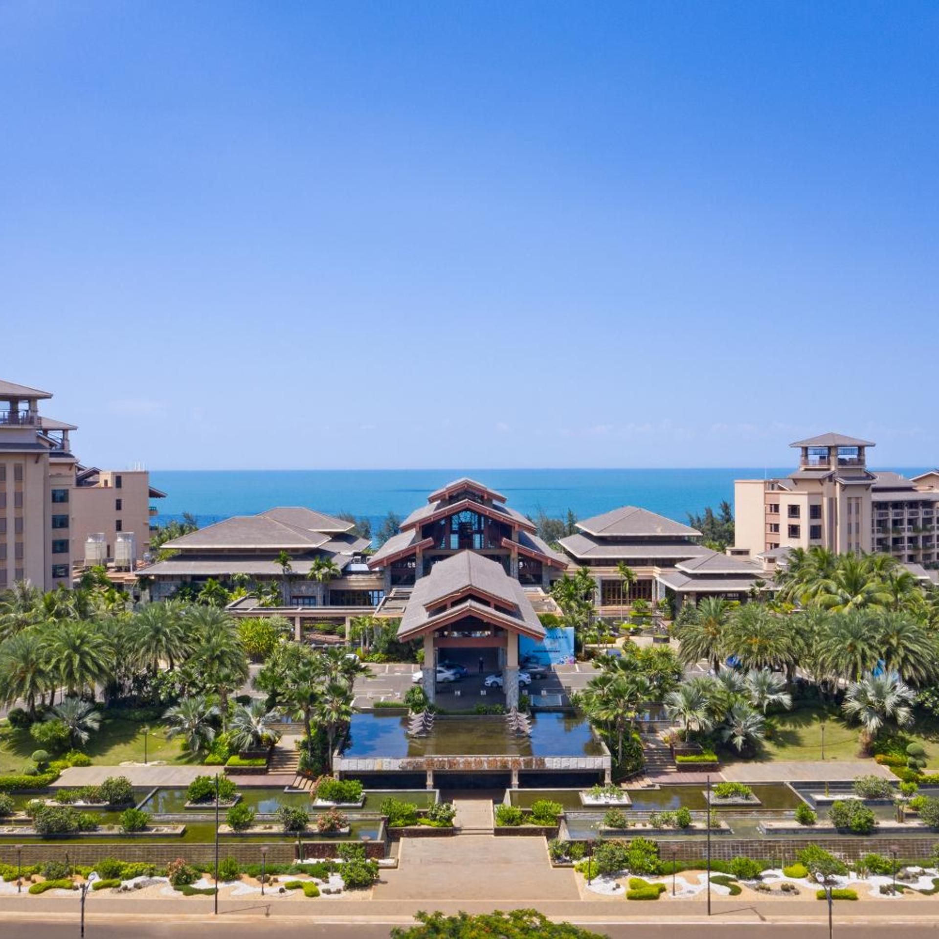 Un resort con varias construcciones, un área de piscina central y vista al océano.