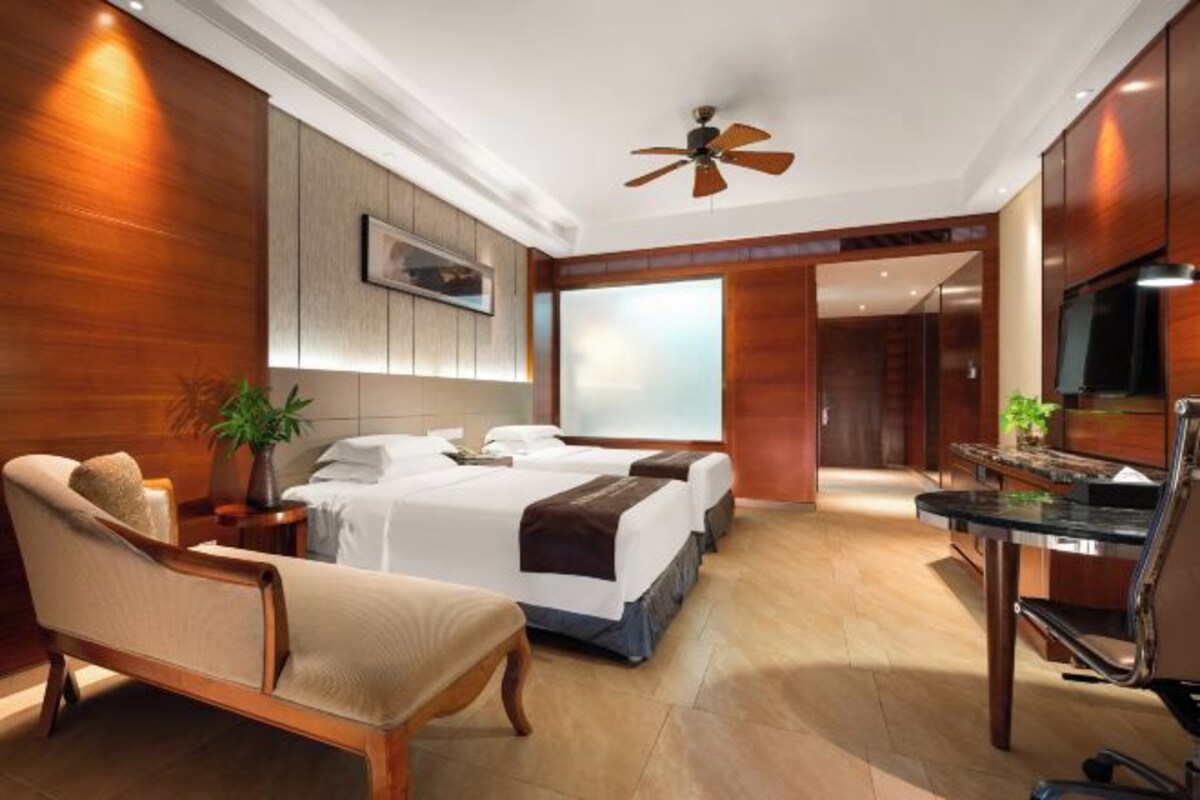 A modern hotel room with a large bed, a desk, and a TV.